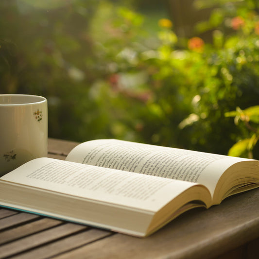 An open book, novel, on top of table with cup of tea